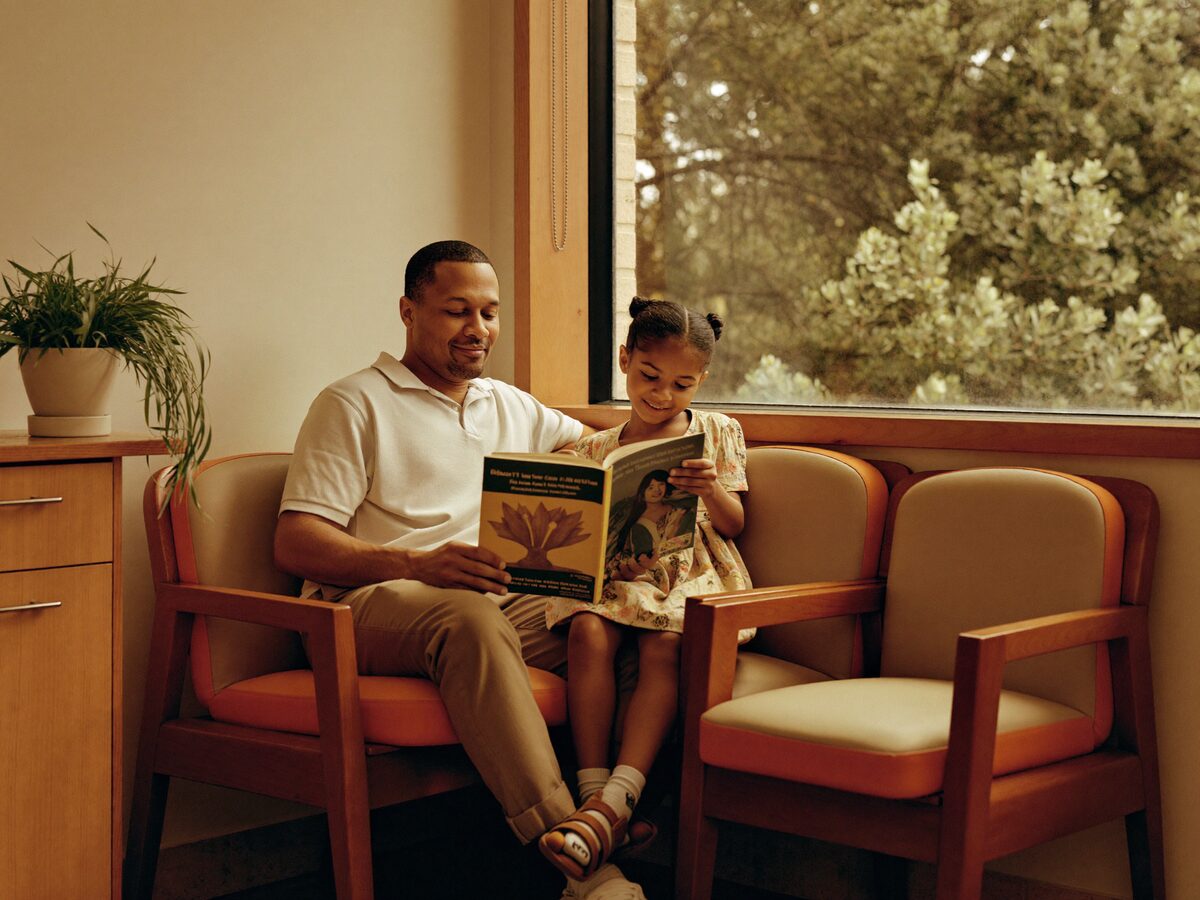 A father and daughter reading together in the friendly waiting room